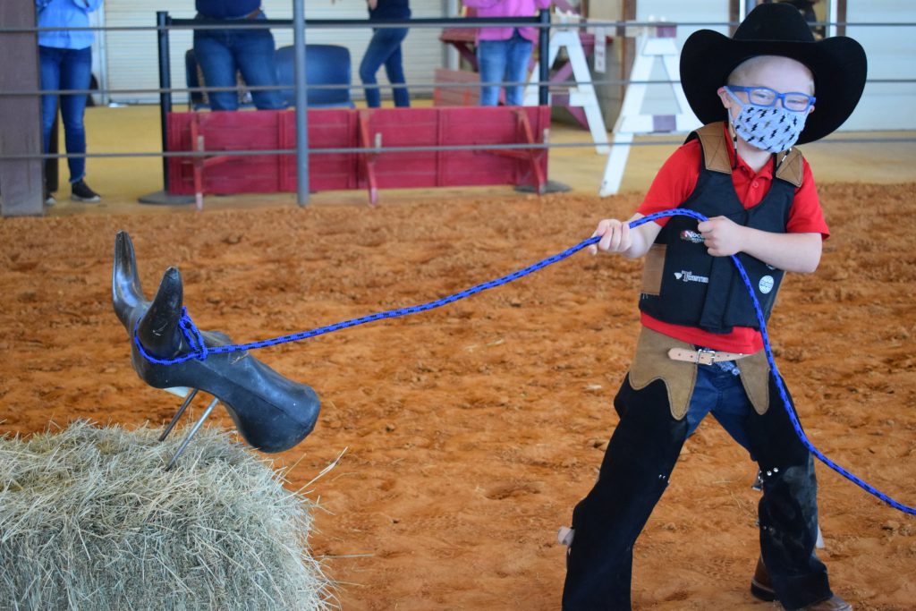 Young cowboy roping a plastic steer head